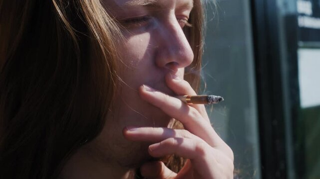 A young chef takes a break from the busy kitchen, smoking a cigarette to unwind.