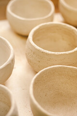 Crafting simple ceramic pots in a pottery studio. Sunlight illuminates the delicate craftsmanship.