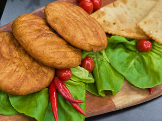 Delightful spread of crispy fried bread served on fresh greens with bright red chilies and tomatoes...