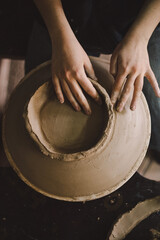 Hands skillfully shape a clay pot in a pottery studio. The workshop encourages creativity and focuses on teaching pottery techniques to beginners in a relaxed atmosphere.