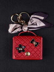 Close up cute leather keychain earphone case red  handbag with decorative charms  on black...