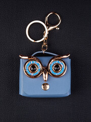 Close up cute leather keychain earphone case  blue  owl eyes handbag on black background