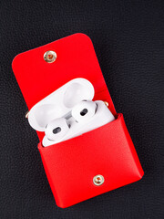 Close up cute leather keychain earphone case red  handbag with decorative charms  on black...