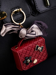 Close up cute leather keychain earphone case red  handbag with decorative charms  on black bag