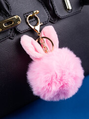 Close up of cute fluffy pink  bunny bag keychain on black bag
