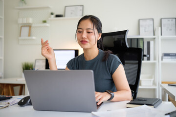 Young businesswoman in a smart casual outfit works on her laptop in a bright office.