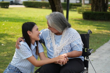 Two women, the daughter pushing a stroller with her elderly mother, walk in the garden and chat happily.
