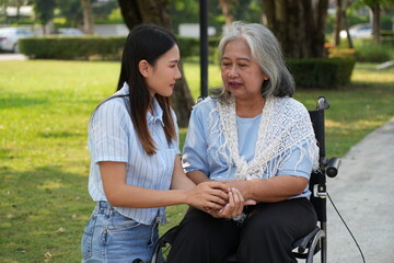Two women, the daughter pushing a stroller with her elderly mother, walk in the garden and chat...