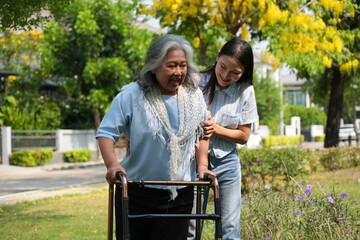 Two women, the daughter pushing a stroller with her elderly mother, walk in the garden and chat happily.