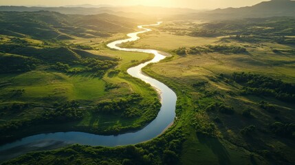 Aerial view of a meandering river flowing through a lush green valley at sunset.