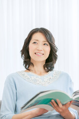リビングで読書をする中年女性