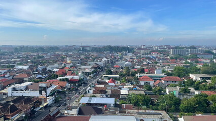 Obraz premium Aerial view of Solo city with traditional red-roofed houses, modern buildings, and clear morning skies blending into the distant horizon.