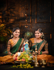 Joyful Asian young sisters in traditional wear arranging Vishu Kani and celebrating the Vishu festival within a decorative background on the occasion of Vishu, Vishu and Janmashtami concept image.