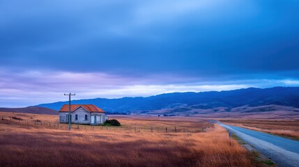 Obraz premium Serene countryside landscape featuring a rustic house by a winding road at dusk