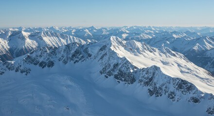 Obraz premium Snow covered mountain range under a clear blue sky aerial view.