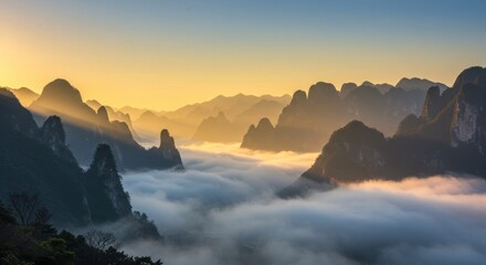 Mountain range with fog or clouds in valley during sunrise or sunset.