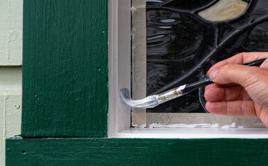 The bristles of a paint brush are bent up while painting a windowsill