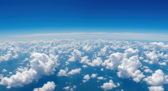 Aerial view of fluffy white clouds against a vibrant blue sky background.