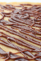 close-up of dark brown chocolate topping of cake surface, criss cross thick irregular wavy lines of pattern, soft focus with blurry background