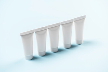 Five white tubes stand in row on blue background.