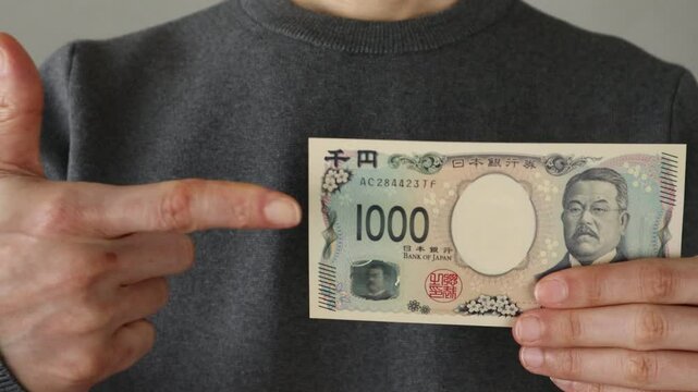 新千円札を指差す人物の動画