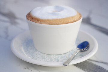 Warm cappuccino served on a saucer with a silver spoon