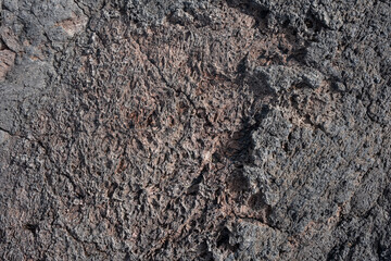 Nahaufnahme einer grau-schwarzen Lava-Textur auf dem Boden. Porös, rissig und steinern, ideal als Stock-Textur oder Foto-Hintergrund. Eindruck von geschmolzenem Gestein.