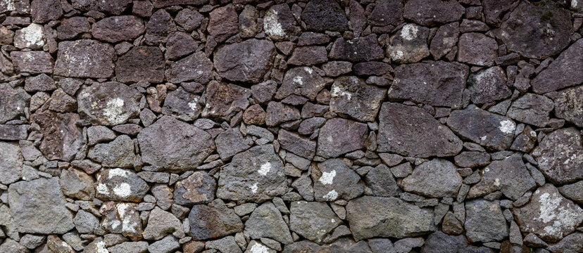Textur Nahaufnahme einer Natursteinmauer aus Lavasteinen auf den Azoren, Portugal. Ohne M&ouml;rtel geschichtet, zeigt sie eine rustikale und nat&uuml;rliche &Auml;sthetik. Eindruck von Stabilit&auml;t und Tradition.