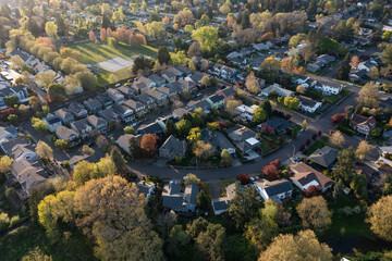 4K aerial drone photo of a peaceful suburban residential neighborhood in Beaverton, Oregon, captured during sunset in spring with visible tennis courts and open green park space