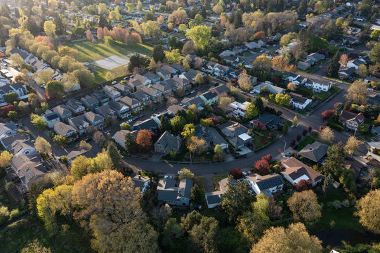 4K aerial drone photo of a peaceful suburban residential neighborhood in Beaverton, Oregon, captured during sunset in spring with visible tennis courts and open green park space