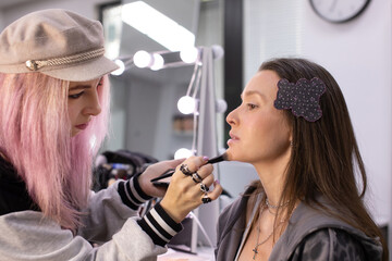Makeup artist work in her beauty studio. Portrait of Woman applying by professional make up master.