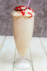 a glass of vanilla milkshake with whipped cream and sprinkles