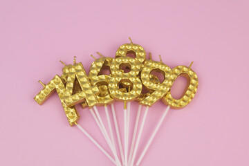 Gold birthday candle on pink background.