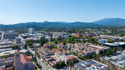 Obraz premium aerial shot of office buildings, apartments and homes with lush green trees and cars on the street in Pasadena California USA