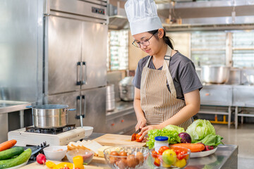 Chef Slicing fresh tomato on Wooden Cutting Board in Professional Kitchen
