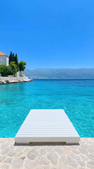 Fototapeta premium White Wooden Jetty Over Turquoise Sea Against Mountain Background
