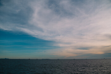 Blue water stretches to the horizon where sea and sky meet, clouds drifting gently as sunlight dances on the ocean, creating a breathtaking natural landscape.