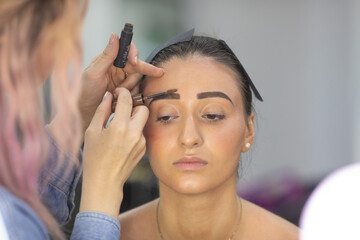 Obraz premium Young woman having makeup applied in beauty salon. Makeup artist. 