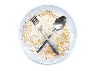 Dirty white plate with food residue with spoon and fork on top isolated on white background 