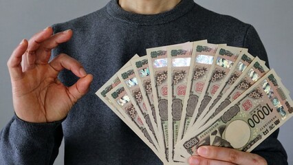 大量の一万円札を持ちポーズする人物