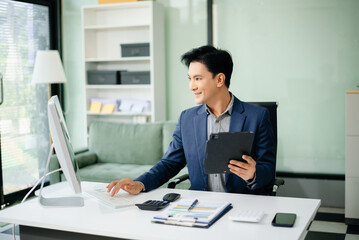 Fototapeta premium Young businessman working with working notepad, tablet and laptop documents talking on the smartphone, tablet and laptop