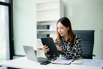 Businesswoman working with working notepad, tablet and laptop documents talking on the smartphone, tablet and laptop