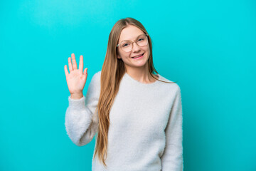 Young Russian woman isolated on blue background saluting with hand with happy expression