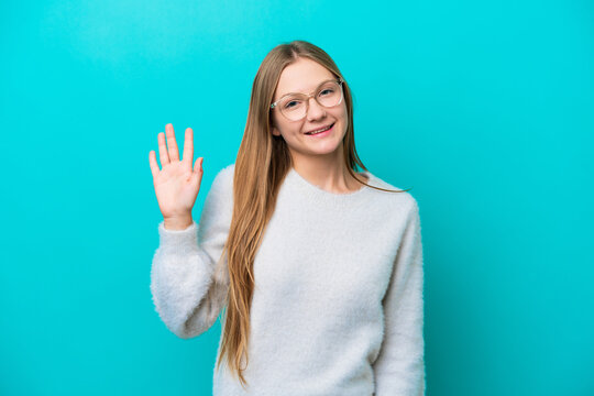 Young Russian woman isolated on blue background saluting with hand with happy expression