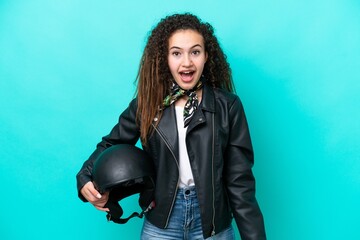 Young Arab woman with a motorcycle helmet isolated on blue background with surprise facial...
