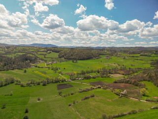 Drone footage of rural hilly landscape with trees and meadows in early spring