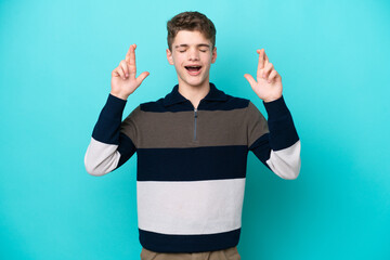 Teenager Russian man isolated on blue background with fingers crossing