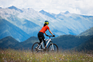 Fototapeta premium Woman riding mountain bike in the beautiful mountains