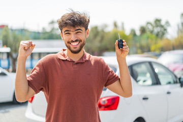 Young Arabian handsome man at outdoors holding car keys and celebrating a victory