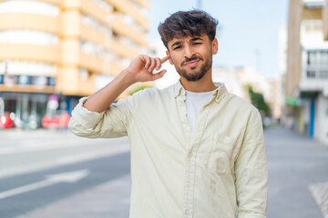 Young Arabian handsome man at outdoors having doubts